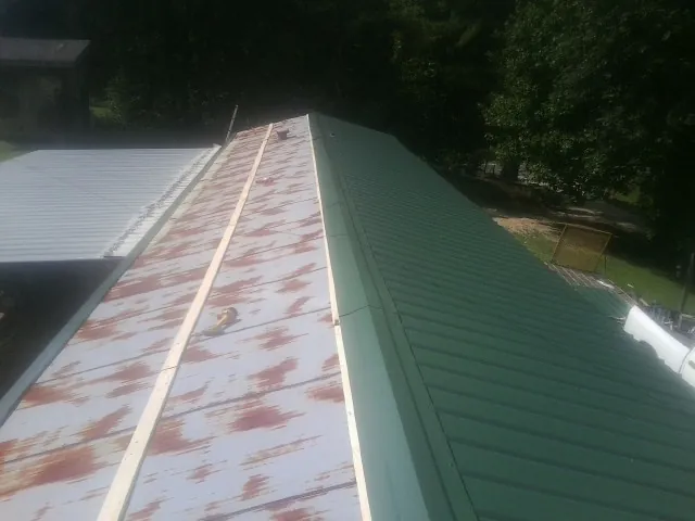 Old rusted panels beside newly installed green metal roofing — Wind Damage Roof Repair by Roofing Brothers in Naugatuck