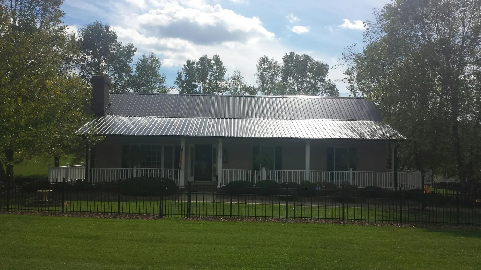 Gray metal roof on a brick ranch with a full width front porch — Gutter Guard Installation work by our crew in Naugatuck