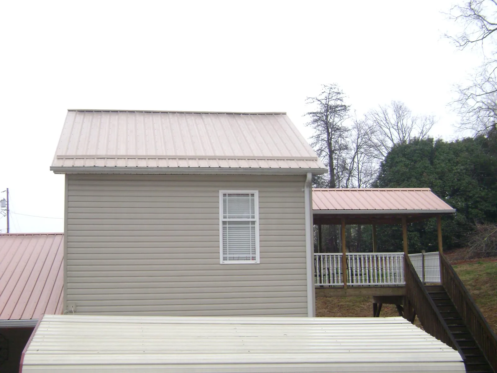 Tan metal roofs on a two story addition and attached porch, from a Roof Replacement job in Naugatuck