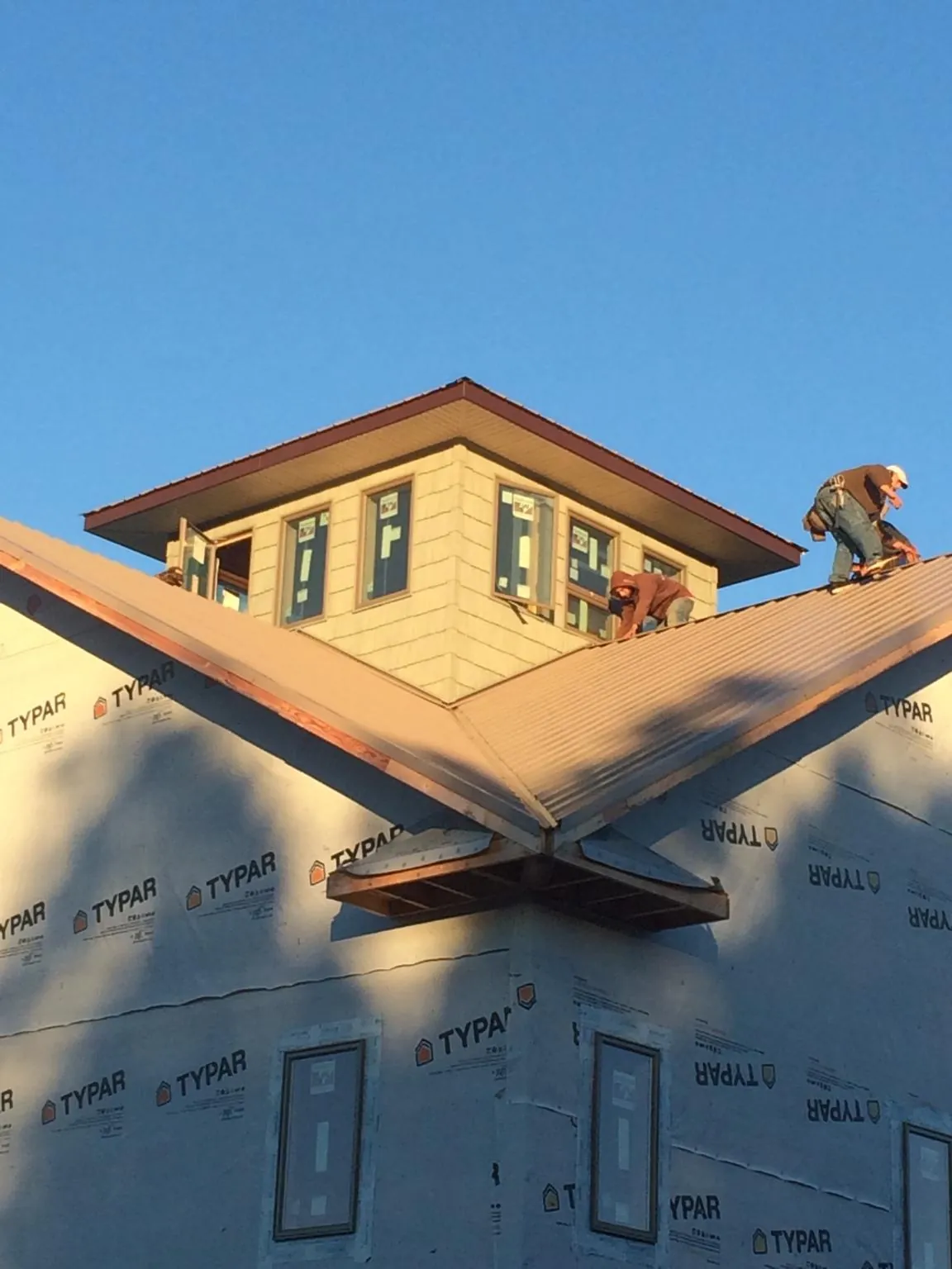 Roofers working around a rooftop cupola on a new metal roof at sunset — Roof Waterproofing in Naugatuck by Roofing Brothers